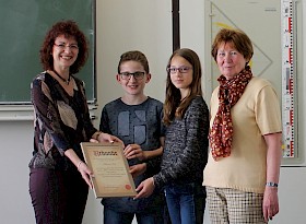 Sandra Mummert und Angelika Wallner (außen) überreichen Lana Steinbrück und Phil Heimhold stellvertretend die Urkunde als Dankeschön für die Spende.