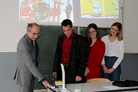 Schulleiter Stefan Ade präsentierte Filialleiter Michael Goth den Visualizer, den die Sparkasse finanziert hatte – die Schülerinnen Cara Fassott und Paula Völker amüsieren sich über den Cartoon.