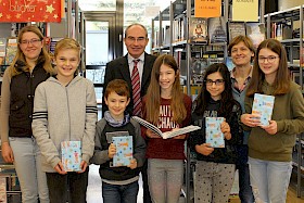 Schulsiegerin Eliza Breitrück liest vor – und Bibliothekarin Veronika Lippolt, Joshua Starke (6d), Ben Norris (6e), Schulleiter Stefan Ade, Laura Pilato (6f), Deutschlehrerin Marion Strommer und Emma Hofacker (6b) haben ihren Spaß.