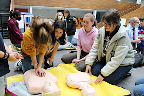 Martina Hanke (links) macht Druckmassage, Mariana Rey schaut zu und Schulsanitäterinnen Ann-Christin Strugies und Jana Dommermuth erklären, worauf Ersthelfer achten sollten.