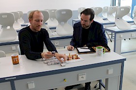 Lehrer Florian Seitz erklärt anhand eines Spiels mit Streichholzschachteln dem Landtagsabgeordneten Andreas Sturm, wie KI funktioniert.